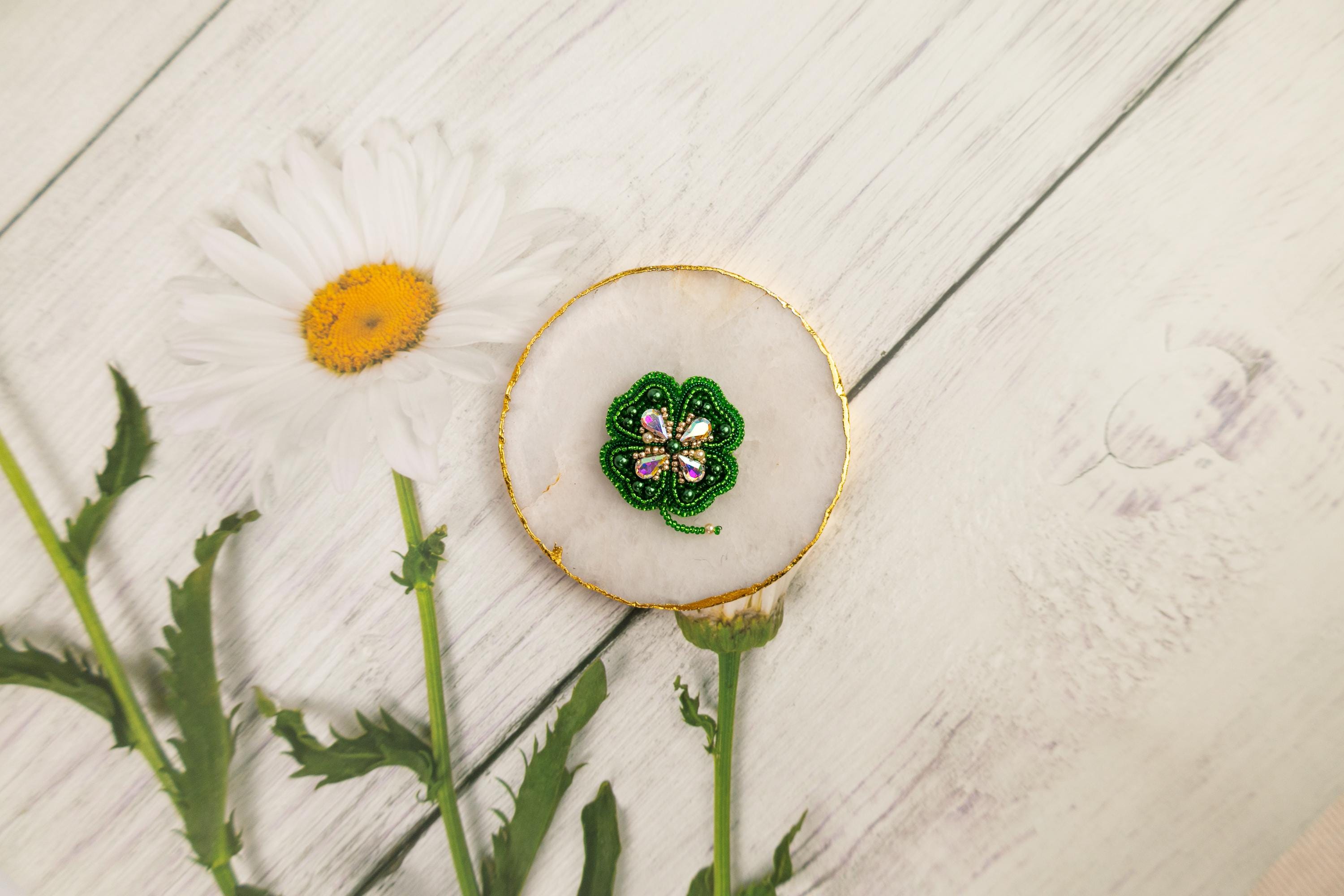 a white flower and a green brooch sitting on a white table